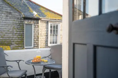 a table with a drink and fruit on a balcony at Stylish Two Bedroom Cottage - In Town Centre in St Ives