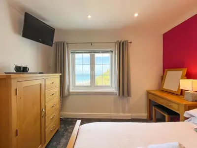 a bedroom with a bed and a window and a desk at Driftwood Spars in St. Agnes