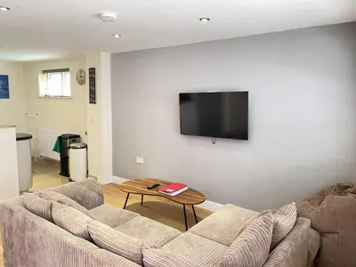 a living room with a couch and a tv on a wall at Harrys Hideout in St Ives