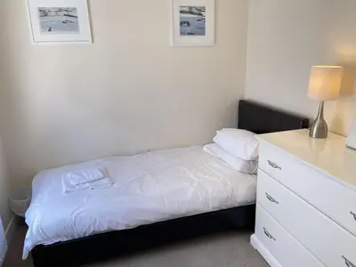 a bedroom with a white bed and a dresser at Rosies Retreat in St Ives