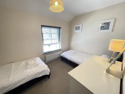 a room with two beds and a desk and a window at Rosies Retreat in St Ives