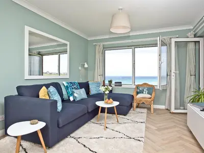 a blue couch in a living room with a view of the ocean at Apartment 8 in Newquay