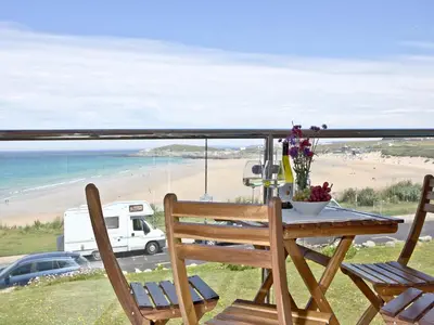 a table and chairs on a balcony with a view of a beach at Apartment 8 in Newquay