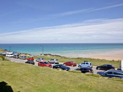 a parking lot with cars parked next to the beach at Apartment 8 in Newquay