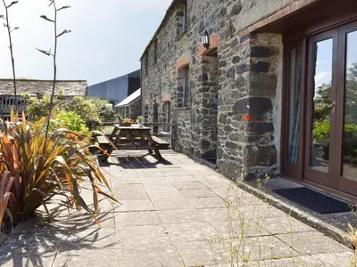 a patio with a table and a stone building at Haywain - Uk12084 in Saint Endellion
