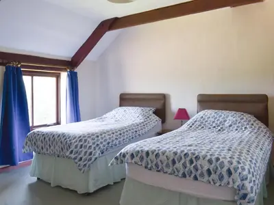 two beds in a room with blue curtains and a window at Haywain - Uk12084 in Saint Endellion