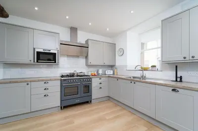 a kitchen with white cabinets and a stove top oven at Harbour Moorings in St Ives