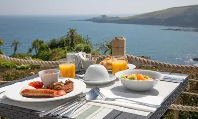 a table with breakfast food on a table with a view of the ocean at Mevagissey Bay Hotel in Mevagissey