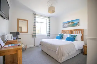a bedroom with a bed with blue pillows at Mevagissey Bay Hotel in Mevagissey