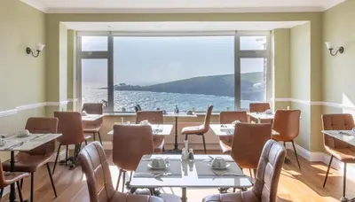 a restaurant with tables and chairs and a large window at Mevagissey Bay Hotel in Mevagissey