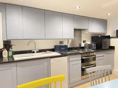 a kitchen with white cabinets and a sink at Sixpence Cottage, a few steps from the harbour! in St Ives