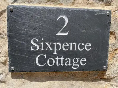 a sign on the side of a stone wall at Sixpence Cottage, a few steps from the harbour! in St Ives