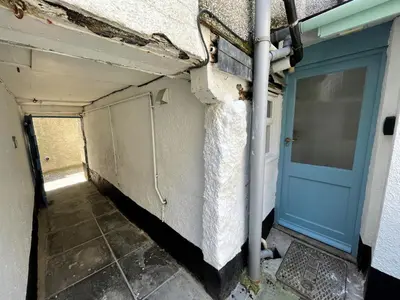 a hallway with a blue door and a building at Sixpence Cottage, a few steps from the harbour! in St Ives