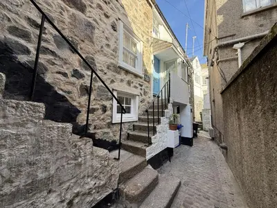 a stone alley with stairs next to a building at Sixpence Cottage, a few steps from the harbour! in St Ives