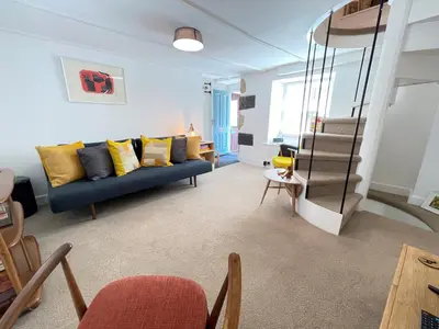 a living room with a blue couch and yellow pillows at Sixpence Cottage, a few steps from the harbour! in St Ives