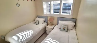 two twin beds in a small bedroom with a window at Ocean's Eddge, Perranporth in Perranporth