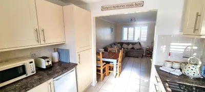 a kitchen and living room with a table and a couch at Ocean's Eddge, Perranporth in Perranporth