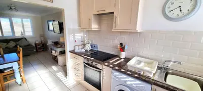 a kitchen with a sink and a clock on the wall at Ocean's Eddge, Perranporth in Perranporth