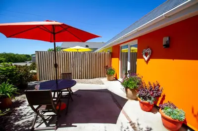 a patio with a table and a red umbrella at Krissie's in Marazion
