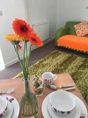 a table with plates and a vase with flowers on it at Krissie's in Marazion