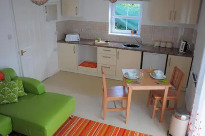 a small kitchen with a table and a green couch at Krissie's in Marazion