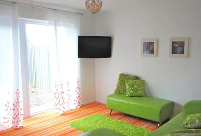a living room with a green couch and a tv at Krissie's in Marazion