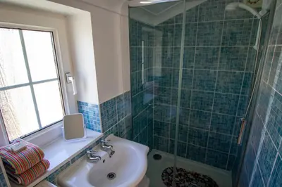 a blue tiled bathroom with a sink and a shower at Krissie's in Marazion