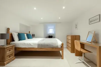 a bedroom with a bed with blue pillows and a desk at Oasis Apartment in Falmouth