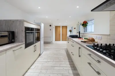 a kitchen with white cabinets and a tile floor at Oasis Apartment in Falmouth