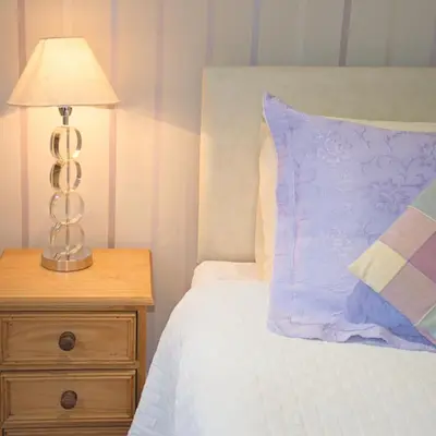 a bed with a lamp on a wooden night stand at Down Ende House Accommodation in Looe