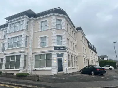 a large white building with a car parked in front of it at Eliot Hotel in Newquay