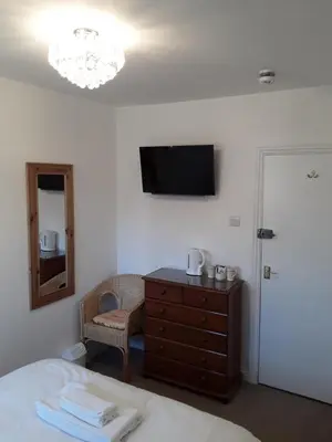 a bedroom with a bed and a dresser and a television at The Mandalay Guest House in Mevagissey