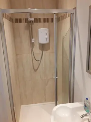 a shower with a glass door and a sink at The Mandalay Guest House in Mevagissey