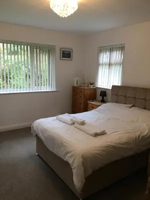 a bedroom with a large bed and two windows at The Mandalay Guest House in Mevagissey