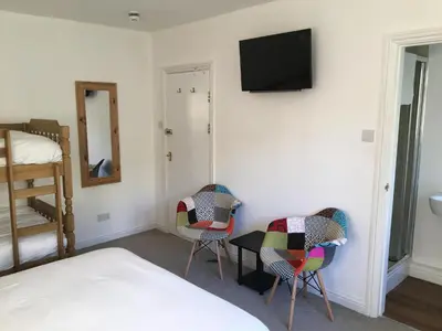a bedroom with a bed and two chairs and a television at The Mandalay Guest House in Mevagissey