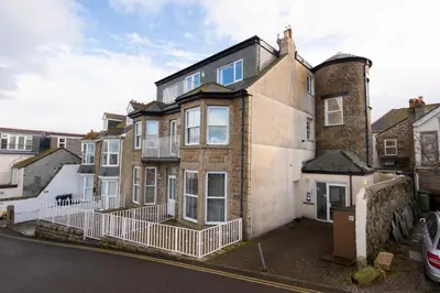a large brick house with a balcony on a street at Waves Apartment, St Ives in St Ives