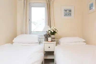 two twin beds in a room with a window at Waves Apartment, St Ives in St Ives