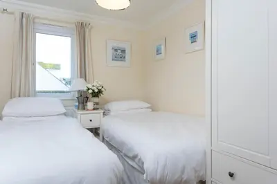 two beds in a white room with a window at Waves Apartment, St Ives in St Ives