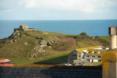 a house on top of a hill next to the ocean at Waves Apartment, St Ives in St Ives