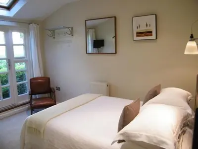 a bedroom with a bed and a mirror and a chair at Spring Cottage B&B in Probus