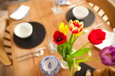 a wooden table with red and yellow flowers in a vase at Spring Cottage B&B in Probus