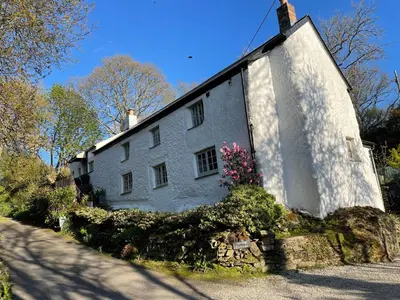 a white house with flowers on the side of it at Spring Cottage B&B in Probus