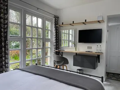 a bedroom with a bed and a desk with a tv at Spring Cottage B&B in Probus