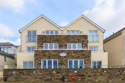 a large brick building with a balcony at The Beach House & Porth Sands Apartments in Newquay