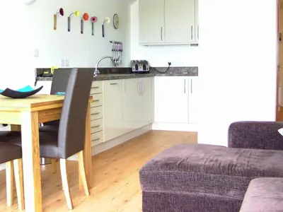 a kitchen with a wooden table and a dining room at The Beach House & Porth Sands Apartments in Newquay
