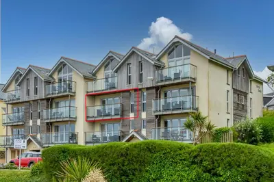 a large apartment building with bushes in front of it at The Beach House & Porth Sands Apartments in Newquay