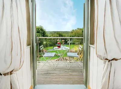 a door open to a deck with a table and chairs at Pear Tree Barn - Amazing Country views - Pet friendly - Balcony in Newquay