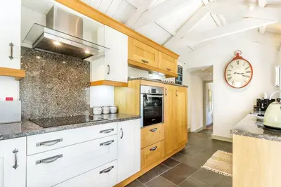 a kitchen with white cabinets and a clock on the wall at Pear Tree Barn - Amazing Country views - Pet friendly - Balcony in Newquay