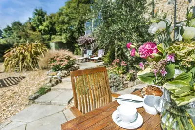 a wooden table with a vase of flowers on it at Pear Tree Barn - Amazing Country views - Pet friendly - Balcony in Newquay
