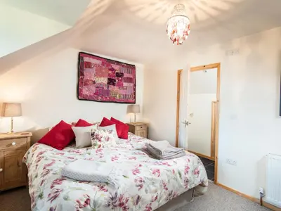 a bedroom with a large bed and a chandelier at Nectan in St Austell